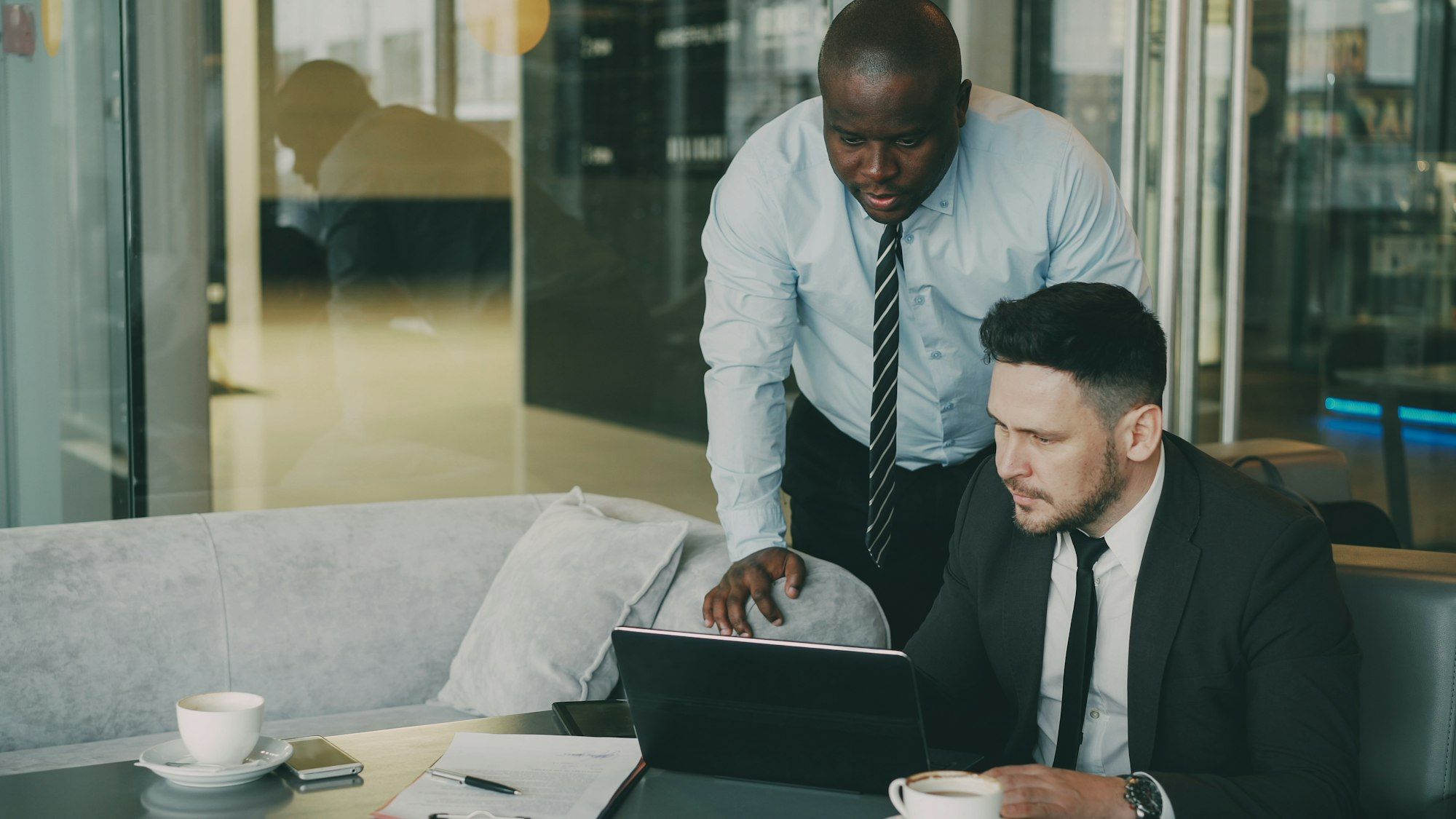 Two colleagues discussing a project at a desk with charts open on a laptop